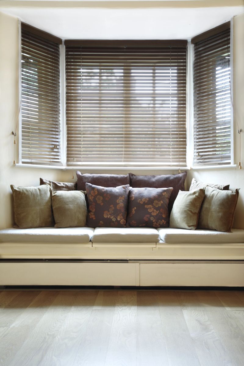 Light and airy living room with wooden blinds at a bay window. Window seat with cushions.