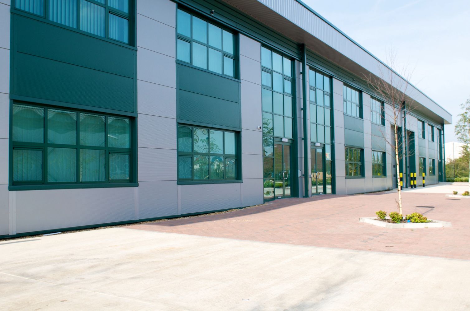 Modern commercial building with glass windows and a paved entrance.