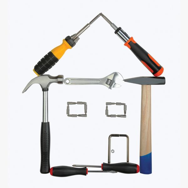 Tools creatively arranged in the shape of a house on a white background.