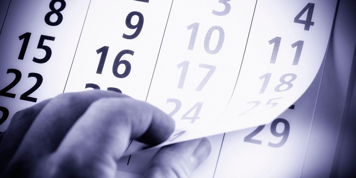 Hand flipping calendar pages showing dates in large numbers.