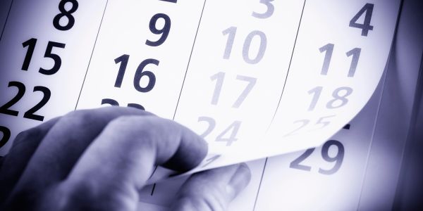 Hand flipping calendar pages showing dates in large numbers.