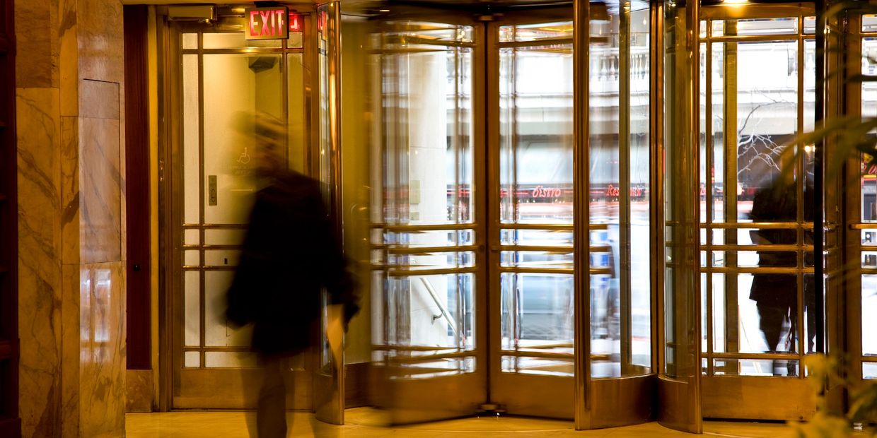 Blurred person near a gold revolving door in a building lobby.