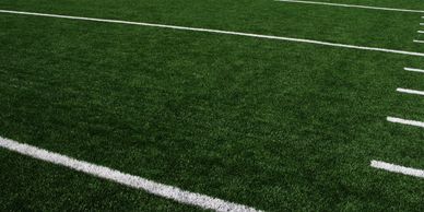 Close-up of a green football field with white yard lines.