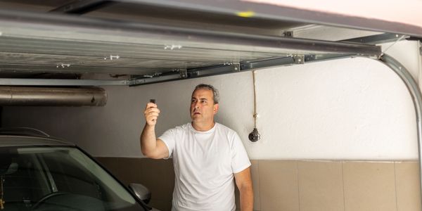 Man closing a garage door using a remote control.
