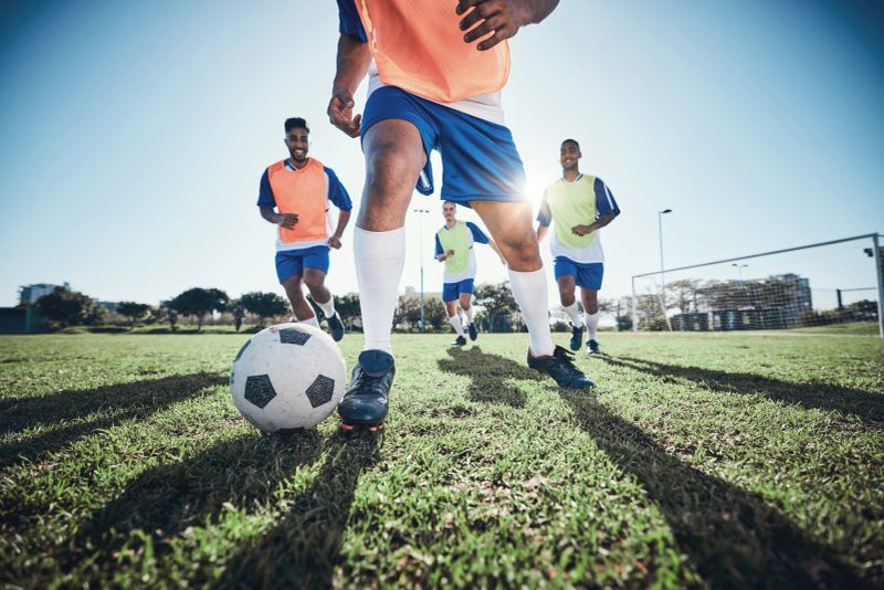 Football, men and exercise with action, field and wellness with workout goal, fitness and competition. Male players, guys and athlete with a challenge, soccer and sports with , energy and training