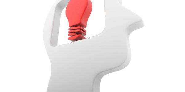 White silhouette of a head with a red light bulb inside symbolizing an idea.