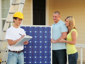 Technician explains solar panel installation to a happy couple at their home.