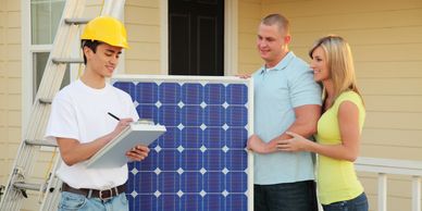 Technician discussing solar panel installation with a smiling couple outside their home.