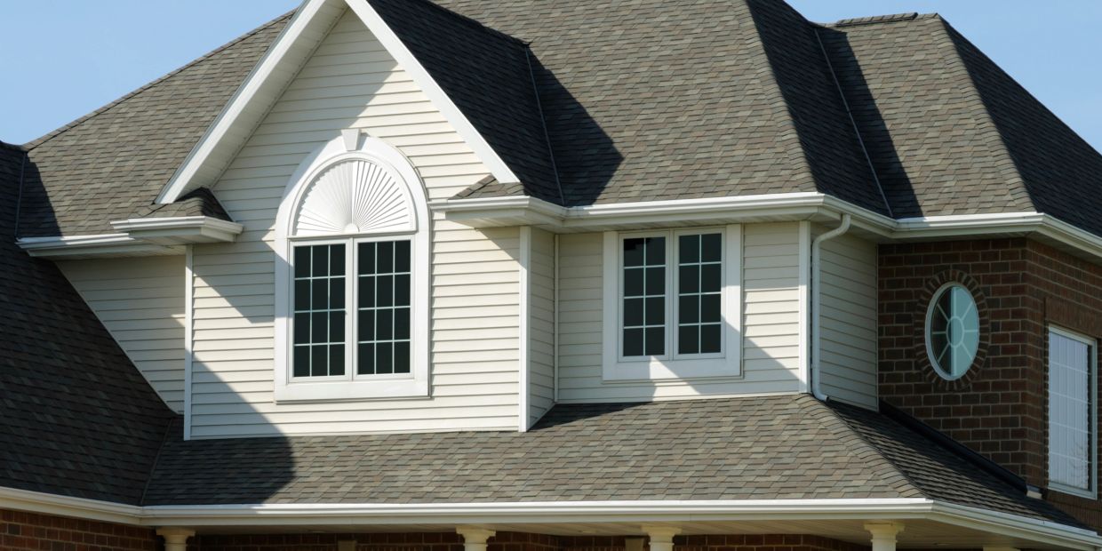 Upper part of a house with multiple windows and a steep roof.