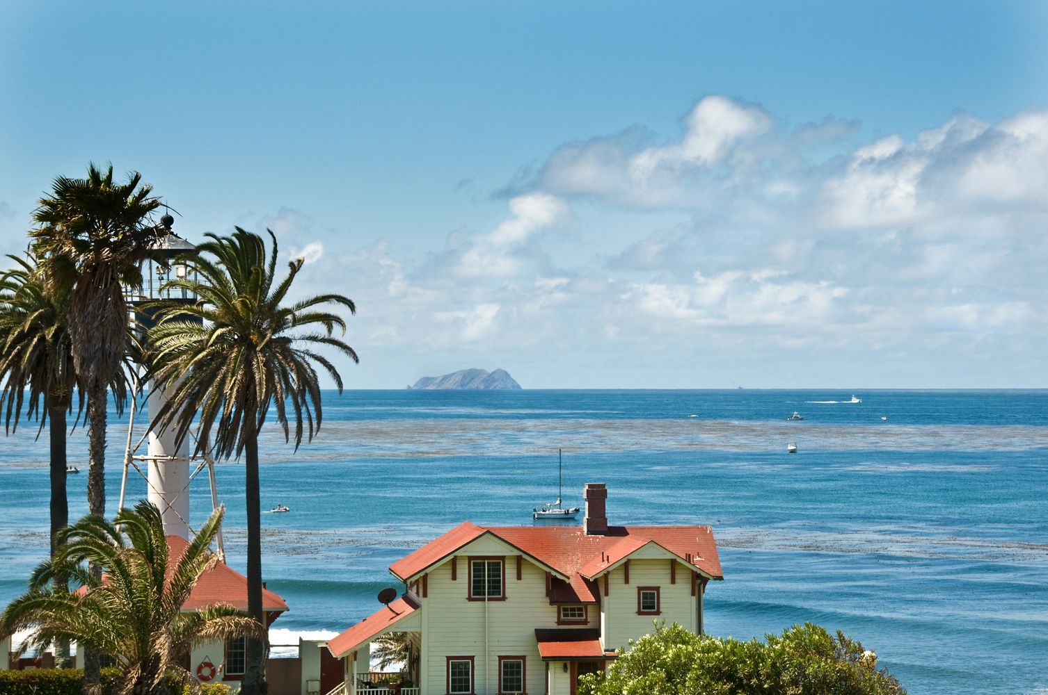 Hand holding a miniature house model with the ocean in the background.