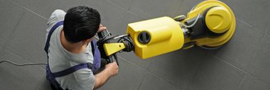 Man using a floor polishing machine on a tiled surface.