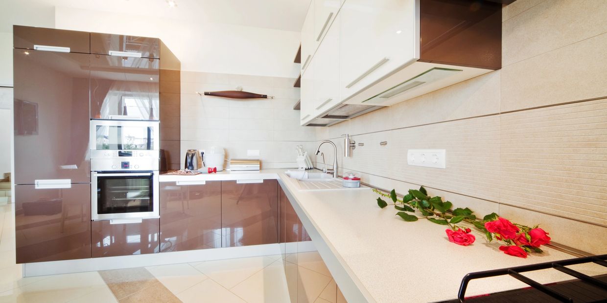 Modern kitchen with glossy brown cabinets and red roses on the countertop.