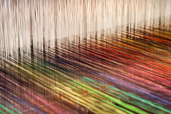 Colorful threads on a loom being woven.