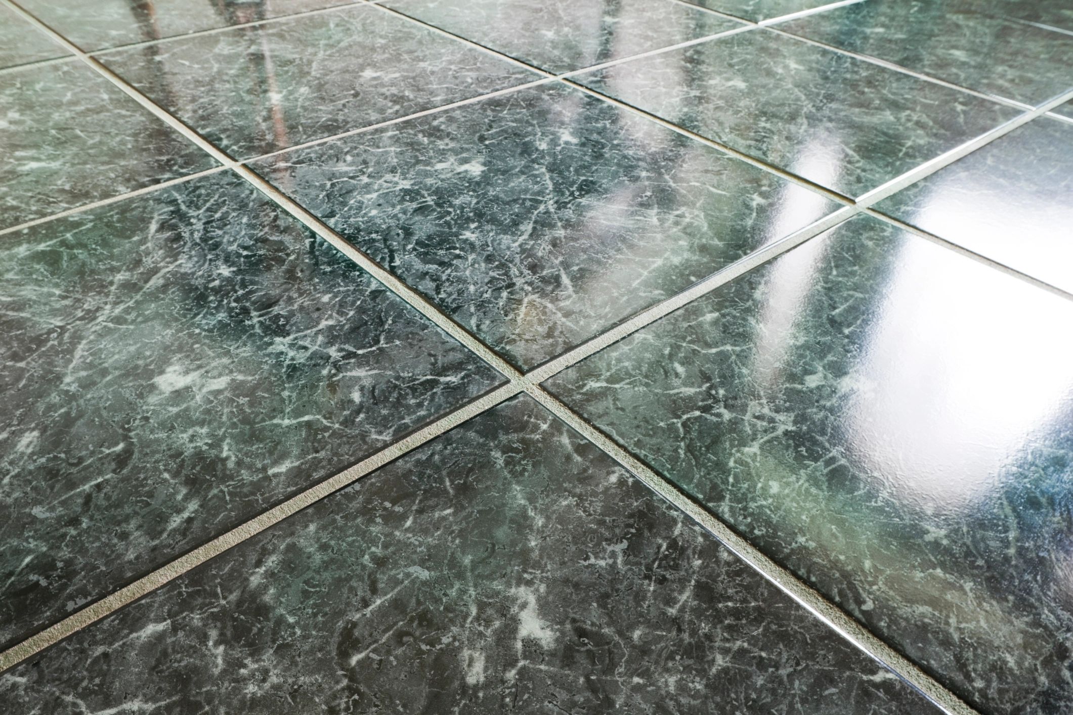 Close-up of glossy dark marble floor tiles with grout lines.