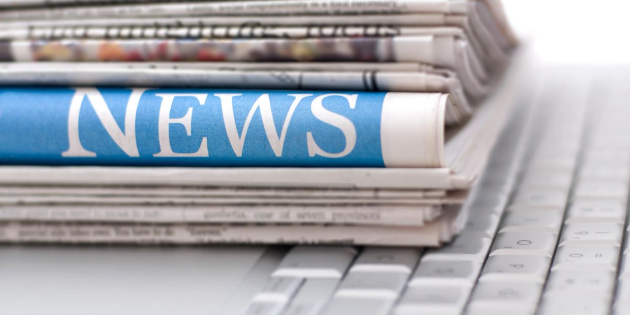 Stack of newspapers on a computer keyboard.