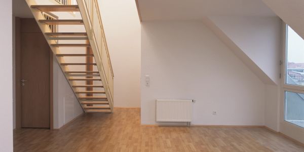 Empty room with wooden floor, staircase, and large window.