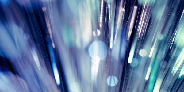Abstract close-up of fiber optic strands with glowing blue and green lights.
