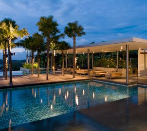 Modern house with large windows and pool at dusk.