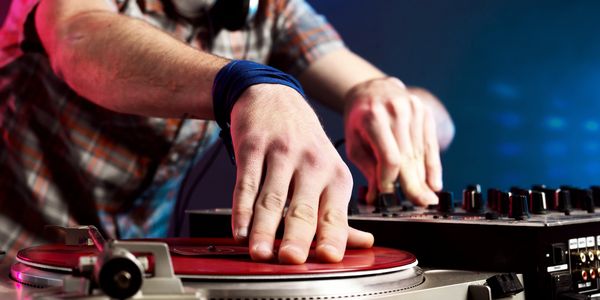 DJ mixing music on a red vinyl record with a mixer.