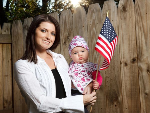 Woman holding a baby with an American flag.