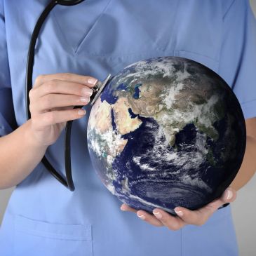 Médico chequeando un globo terráqueo con un estetoscopio.