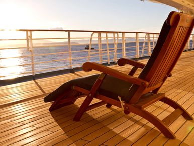 Wooden deck chair on a ship at sunset.