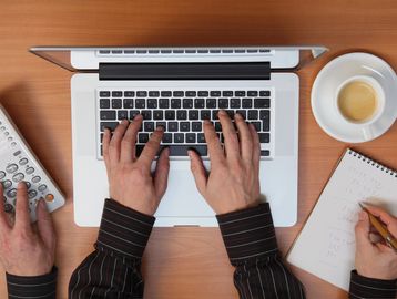 hands typing on a laptop keyboard.