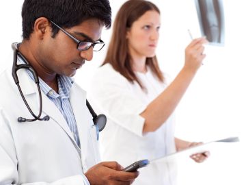 Two doctors analyzing medical images and using a smartphone.