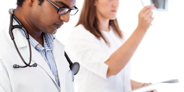 Two doctors analyzing patient information and X-rays in a clinical setting.