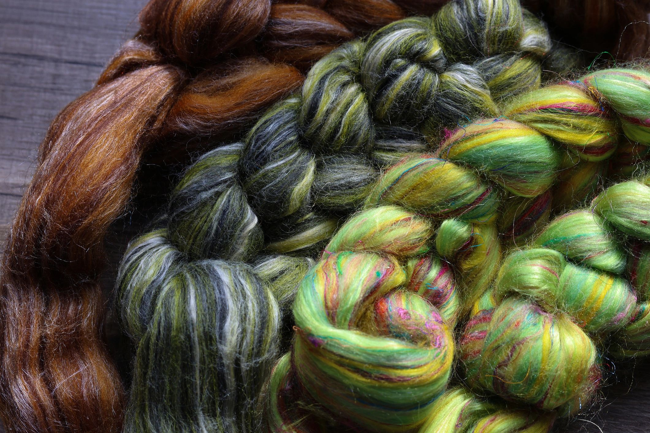 Closeup detail of colourful sheep wool merino, alpaca and silk fibres in a roving pleat, ready for spinning on traditional spinning wheel.