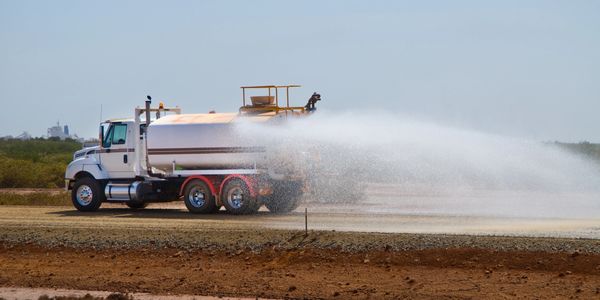 Water truck spraying water on a dry surface.