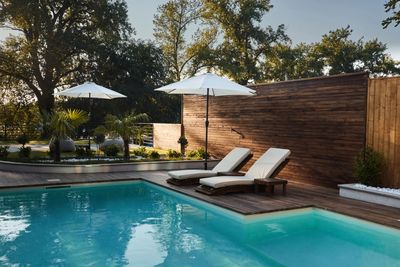 Modern backyard pool with lounge chairs and umbrellas in the evening.