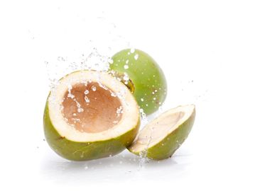 Fresh green coconut cut open with water splash.