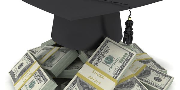 Graduation cap on stacks of hundred-dollar bills symbolizing education costs.