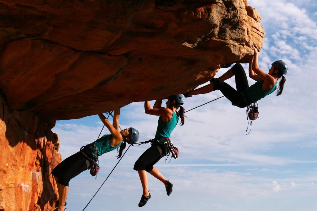Woman rock climbing on an overhang wearing safety gear.