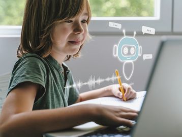 A child interacts with a chatbot while writing and using a laptop.