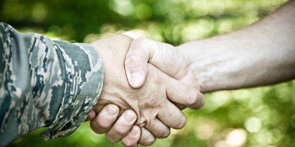 Handshake between a person in military uniform and a civilian.
