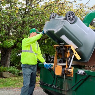 Sanitation worker empties a trash bin into a garbage truck.