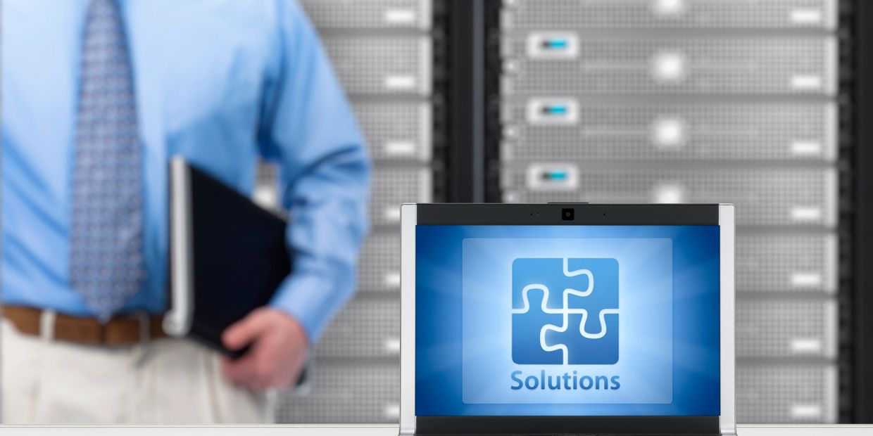 Laptop displaying a puzzle piece graphic labeled 'Solutions' in a server room.