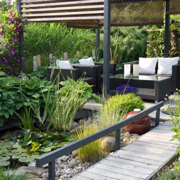 Cozy outdoor seating area beside a garden pond.