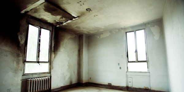 An empty, dilapidated room with peeling walls and damaged ceiling.