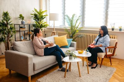Two women in a therapy session in a cozy living room.