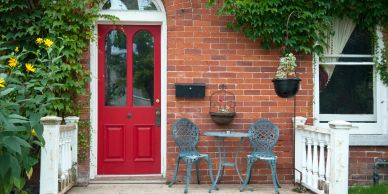 Red door with outdoor seating and greenery.