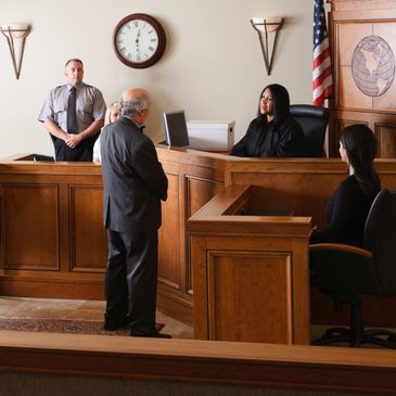 Judge speaking to a man in a courtroom with a police officer and others present.