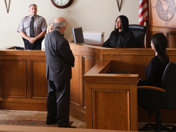 A judge listens to a man in a courtroom during a legal proceeding.