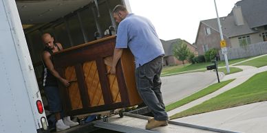 Two men loading a piano into a truck.