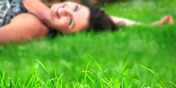 A woman lying on the grass, smiling joyfully.