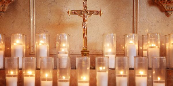 Lit candles in front of a crucifix.