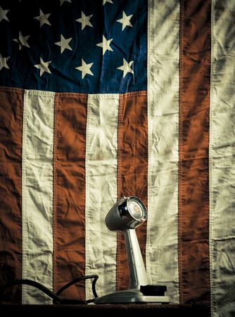 A vintage microphone in front of an American flag.