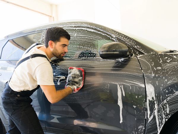 Wiping soapy dark car exterior.